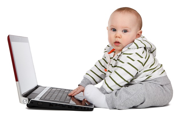 A baby sitting in front of a laptop computer